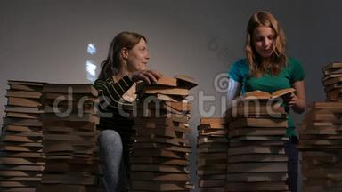 两个女孩，母亲和她十几岁的女儿，或者两个姐妹正在看书，玩书。 4KUHD。