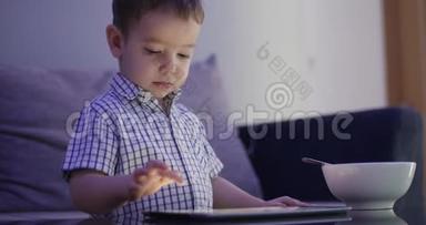 可爱的孩子用平板电脑娱乐。 小男孩把闲暇时间花在玩手游上，把明亮的阳光压得粉碎