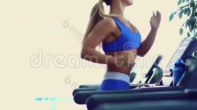 年轻的健身妇女在健身房做有氧运动，在跑步机上跑步。