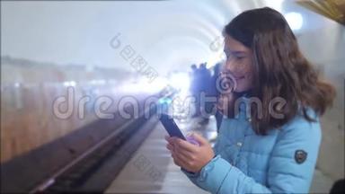 少女在地下<strong>地铁</strong>里乘<strong>地铁</strong>等待火车的到来，手持智能手机.. 小可爱