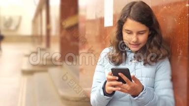 少女在地下地铁中乘坐地铁等待生活方式列车的到来，手持智能手机