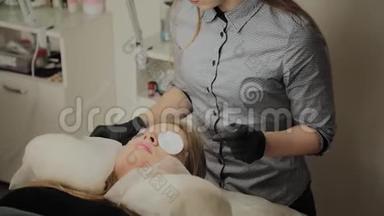 一个非常漂亮的女孩在美容院做一个层叠睫毛。 美容师做睫毛手术
