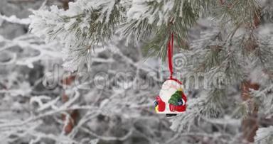 新年。 圣诞节和装饰品。 一个红色的玩具圣诞老人在森林里的树枝上摇摆。 下雪