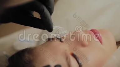 一个非常漂亮的女孩在美容院做一个层叠睫毛。 美容师做睫毛手术