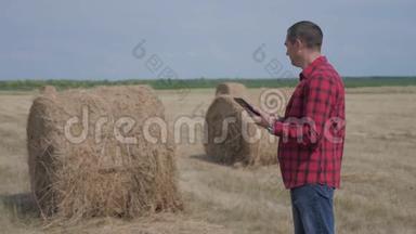 智慧农业理念.. <strong>生活</strong>方式男子工人农民在数字平板电脑上的田野上研究干草堆。 <strong>慢慢慢慢</strong>