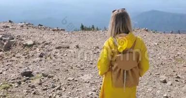徒步旅行者背着背包在<strong>山顶</strong>徒步旅行。 穿着黄色雨衣的女孩在<strong>山顶</strong>上