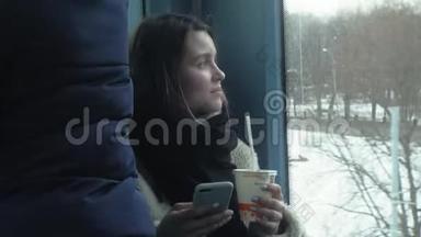 年轻的黑发女人乘坐公共交通工具，带着耳机使用电话