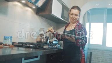 女人在厨房煮汤，防止锅中的水，看看数字平板上的食谱。 妇女