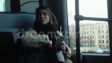 年轻的黑发女人乘坐公共交通工具，带着耳机使用电话