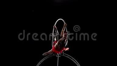 <strong>灵活</strong>的体操运动员在空中箍金属结构上表演技巧。 黑色背景。 慢动作
