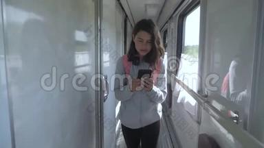 十几岁的女孩走在火车车厢里，背着背包，生活方式是智能手机。 <strong>交通运输</strong>