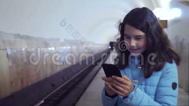 少女在地下地铁里乘地铁等待火车的到来，手持智能手机.. 小可爱