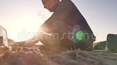 自由职业者。 一个在笔记本电脑上工作的人，自由职业者，坐在沙滩上，夕阳，阳光