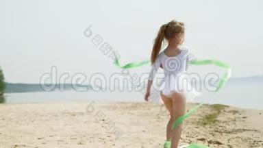 学龄前女孩带着体<strong>操</strong>丝带在沙滩上<strong>跳</strong>舞。 夏天，黎明