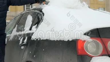 人从雪地里清洁汽车