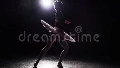 年轻而美丽的芭蕾舞女演员在黑色背景下优雅地在她的尖角芭蕾舞鞋上跳舞