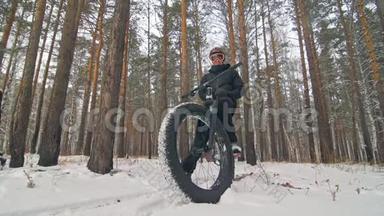 职业极限运动员骑自行车在户外坐一辆胖自行车。 骑自行车者在冬天的雪林中退缩。 与人<strong>同行</strong>