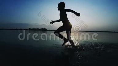 日落时沿着海滩奔跑的快乐儿童剪影。 慢动作