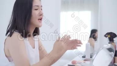 幸福美丽的年轻亚洲女人用化妆品评论化妆教程直播视频到社交网络。