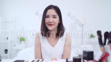 幸福美丽的年轻亚洲女人用化妆品评论化妆教程直播视频到社交网络。