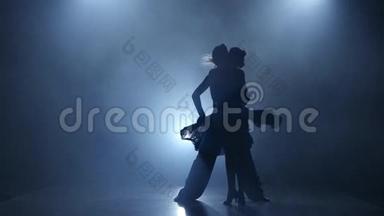 舞蹈探戈由职业情侣在烟雾弥漫的工作室表演，剪影