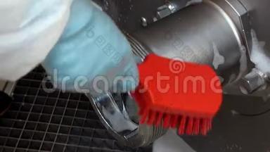 用红色泡沫刷手套清洗钢工业绞肉机。