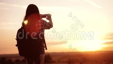 hipsterhiker剪影生活方式女孩正在手机智能手机上拍摄美丽自然日落的视频