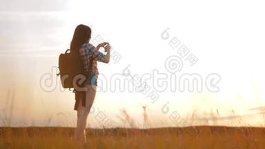 hipsterhiker剪影女孩正在手机智能手机上拍摄美丽自然日落的视频