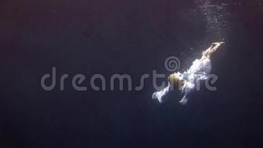 年轻女孩在红海的蓝色背景上模特水下白色天使服装。