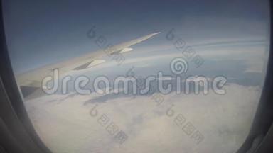 透过飞机窗户观看云层上方的飞机机翼