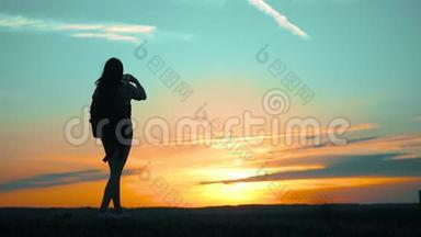 希普斯特的剪影女孩正在手机智能手机上拍摄美丽自然日落的视频