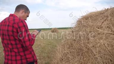 智慧农业理念.. 农夫在数字平板电脑上的田野里研究干草堆。 慢速视频