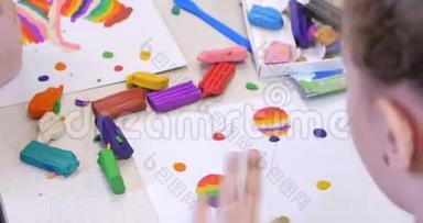坐在办公桌前的可爱的小孩子从彩色造型塑料制成的图形中提取出不同的图形
