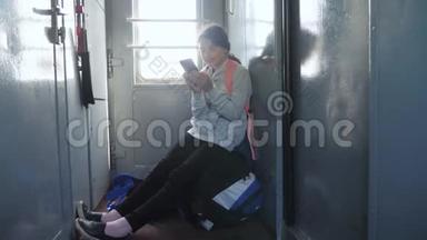 年轻的女孩旅行者带着一个背包，坐在装有智能手机的车窗上的背包上。 <strong>旅游线</strong>路