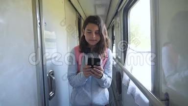 十几岁的女孩带着背包和智能手机在<strong>火车车厢</strong>里散步。 旅游运输铁路概念。 (a)