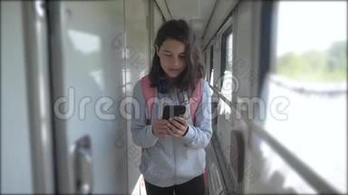 十几岁的女孩走在<strong>火车车厢</strong>里，带着背包的生活方式和智能手机。 交通运输