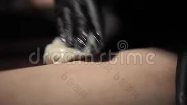 美容师从一个年轻女人的腿上取下头<strong>发</strong>糖<strong>膏</strong>。