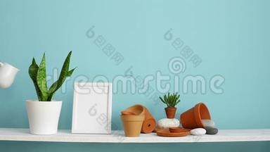 现代客房装饰与相框模型。 白色的架子，贴着青绿色的墙壁，上面有陶器和肉质植物。 手