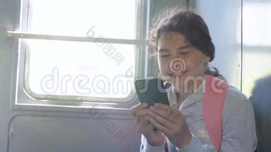 年轻的女孩旅行者带着一个背包，坐在装有智能手机的车窗上的背包上。 <strong>旅游线</strong>路