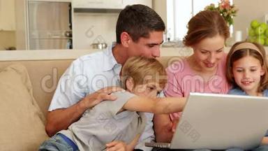 幸福的一家人一起坐在沙发上用笔记本电脑