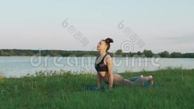 美丽的年轻女子早上在蓝色瑜伽垫上做瑜伽，安静的风景