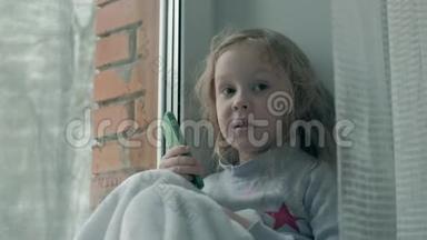快乐的小女孩，一头波浪状的红色头发，坐在窗台上，盖着毯子，用电话，说话，视频