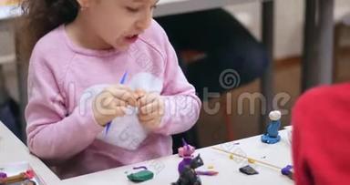 坐在办公桌前的<strong>可爱</strong>的小孩子从彩色<strong>造型</strong>塑料制成的图形中提取出不同的图形