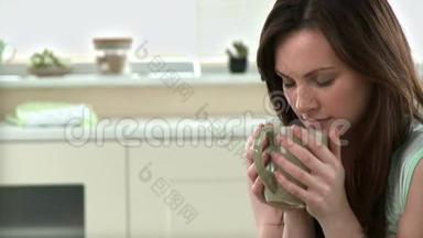 放松的女人在厨房里喝咖啡