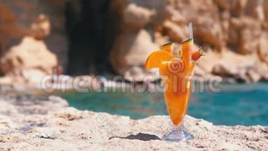 埃及海滩上的麦秆玻璃中的热带鲜榨果汁矗立在海边的岩石上