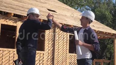 团队合作。 概念建设构建建筑师慢动作视频。 两个男人戴头盔，生活方式握手