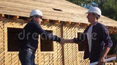 团队合作。 概念建筑构建建筑师慢动作视频.. 两个戴头盔的工人握手合同