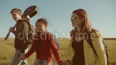 快乐家庭慢动作视频行走在大自然男孩女孩和妈妈在野外徒步旅行。 带吉他的游客
