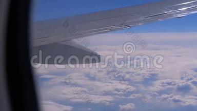 从云层上的飞机窗口观看。 一架飞机飞过云层的翅膀