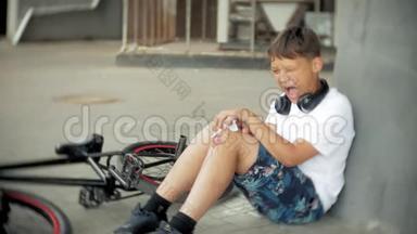 一个小男孩从自行车上摔下来后坐在公园里，膝盖的疼痛得到缓解，这是一辆危险的自行车